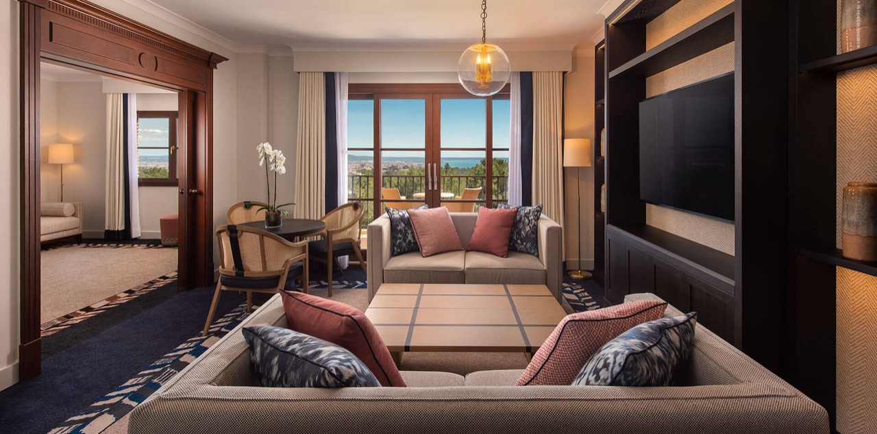 Suite living room with sofas and a balcony overlooking the bay