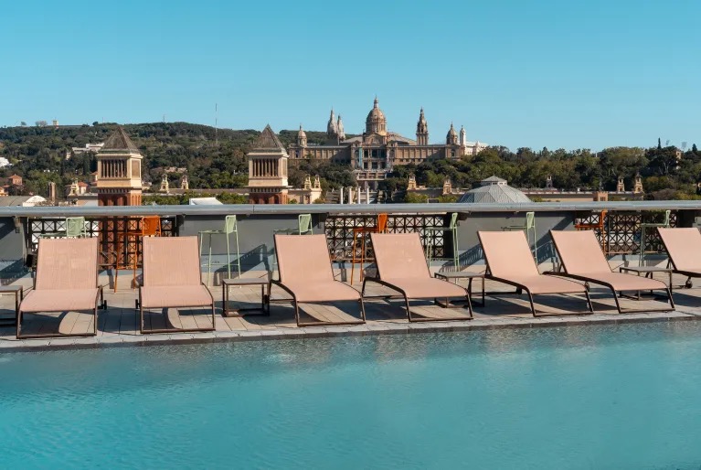 Rooftop pool with loungers and a view of the Palau Nacional