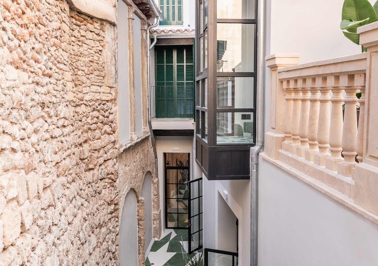 Stone building exterior and balustrade seen from a narrow alley beside the hotel