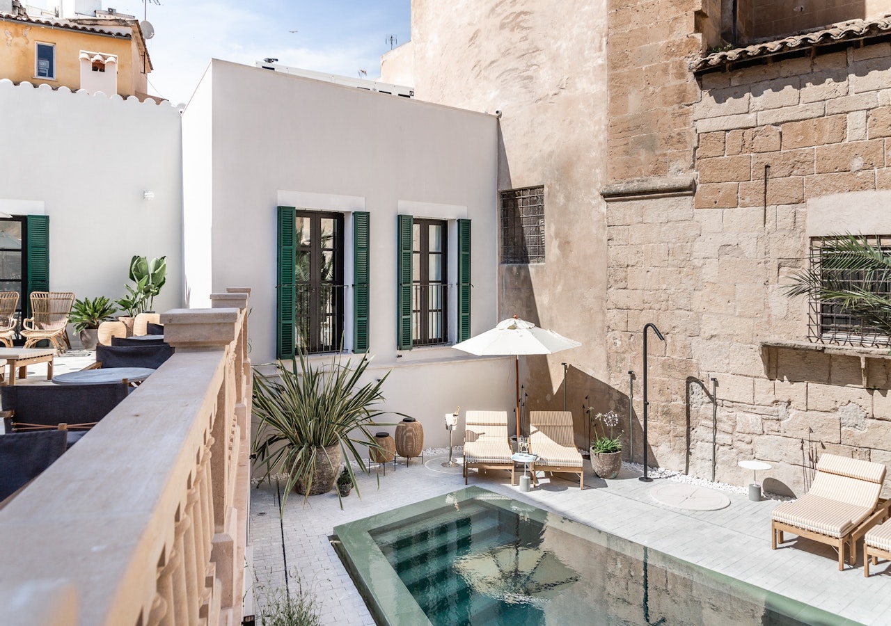 Small plunge pool on a rooftop terrace with sun loungers against the old town stonework
