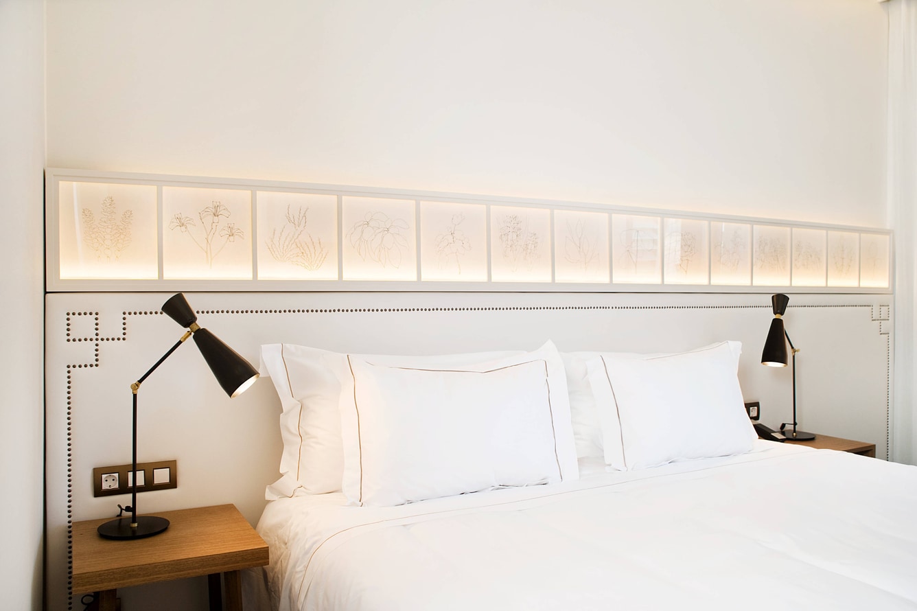 Guest room bed set against a botanical-illustration headboard panel