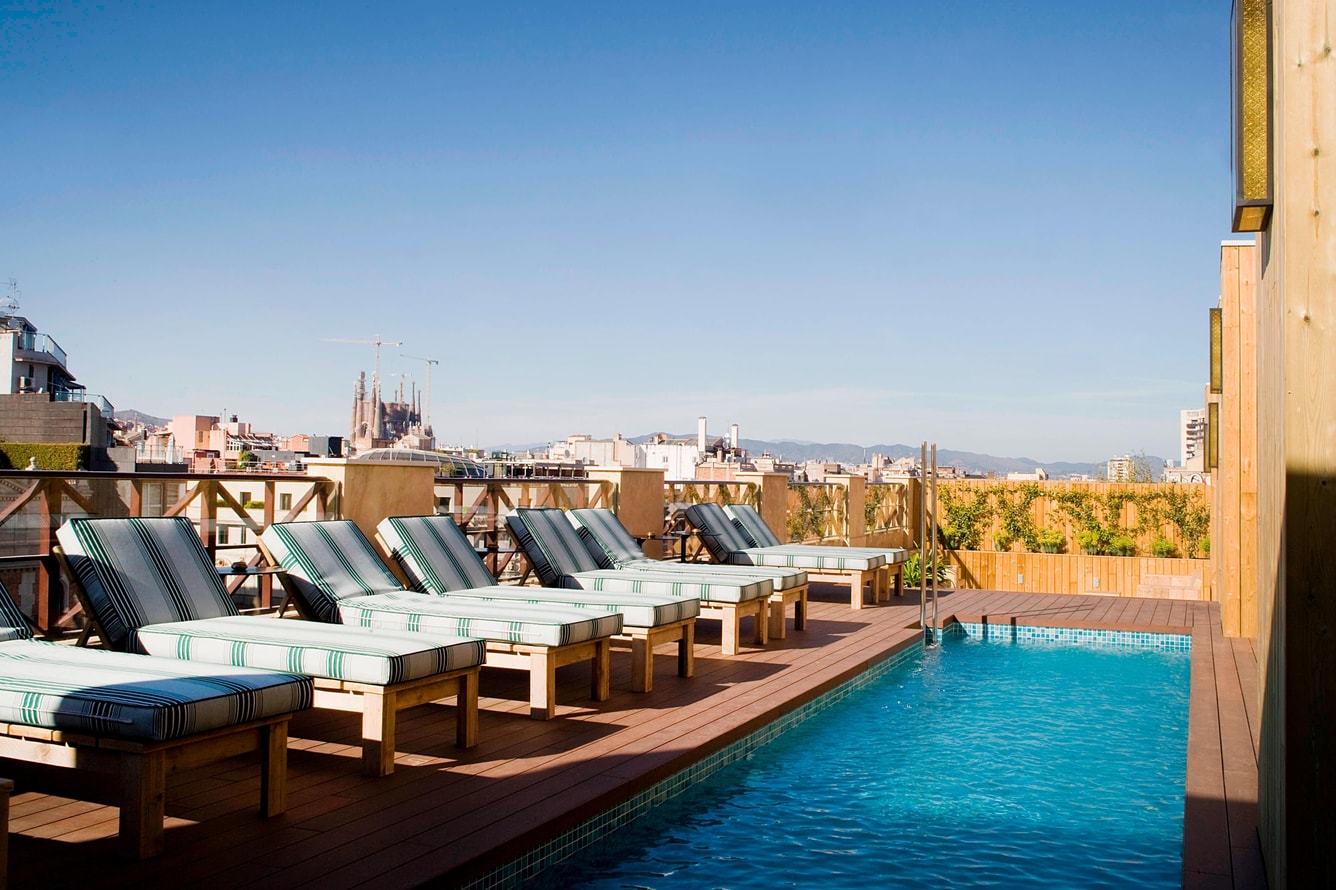 Rooftop pool with striped loungers and the Sagrada Família on the skyline