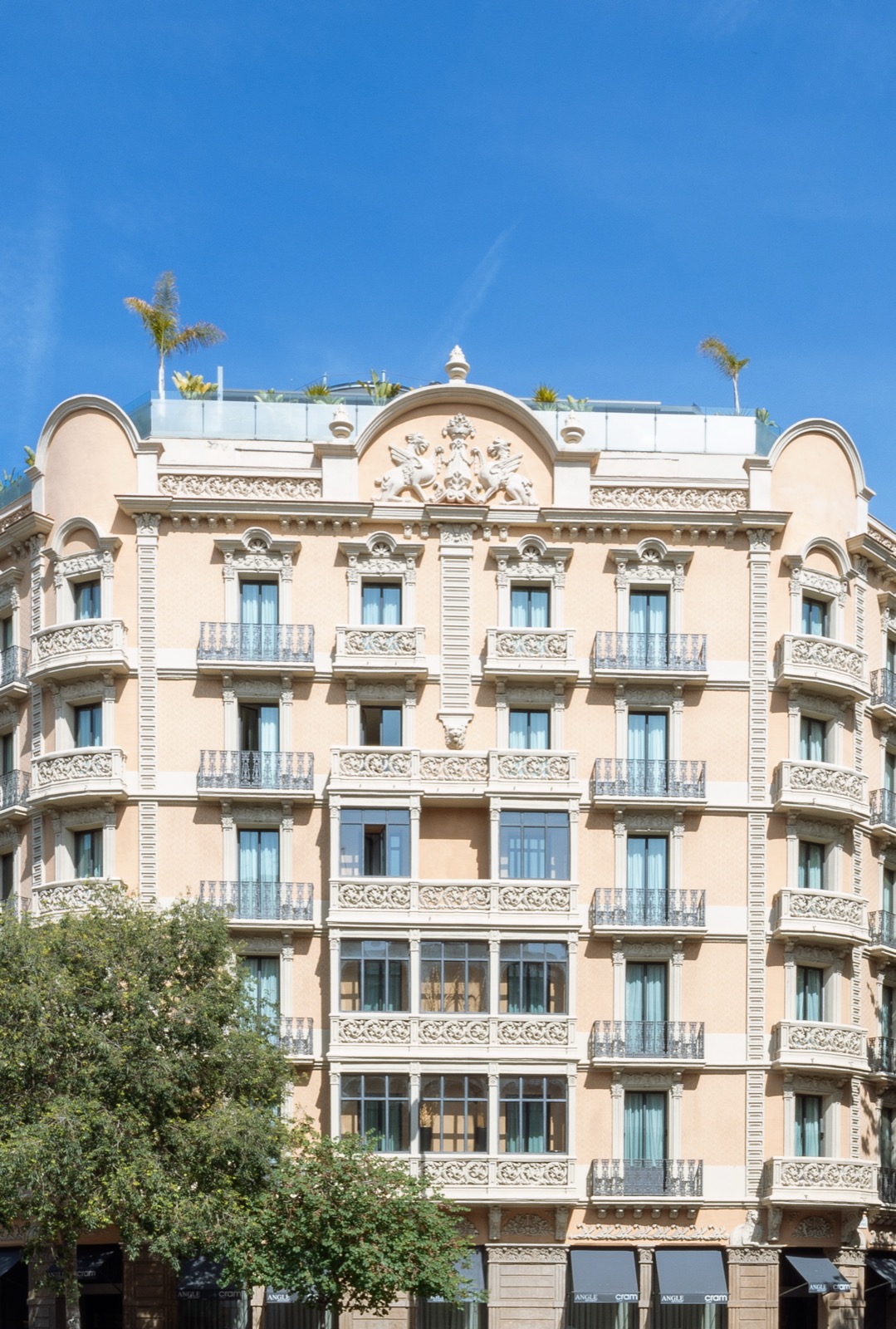 Hotel Cram's facade with wrought-iron balconies and rooftop palms