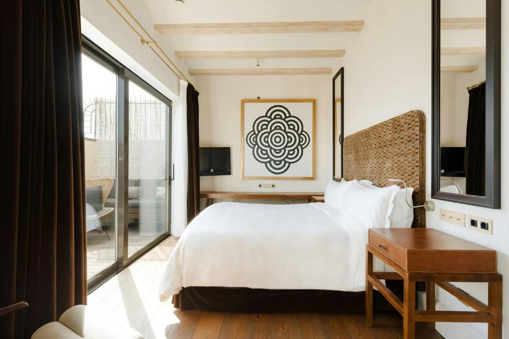 Guest room at Hotel DO: Plaça Reial with a woven headboard, wooden ceiling beams and glass doors onto a private terrace