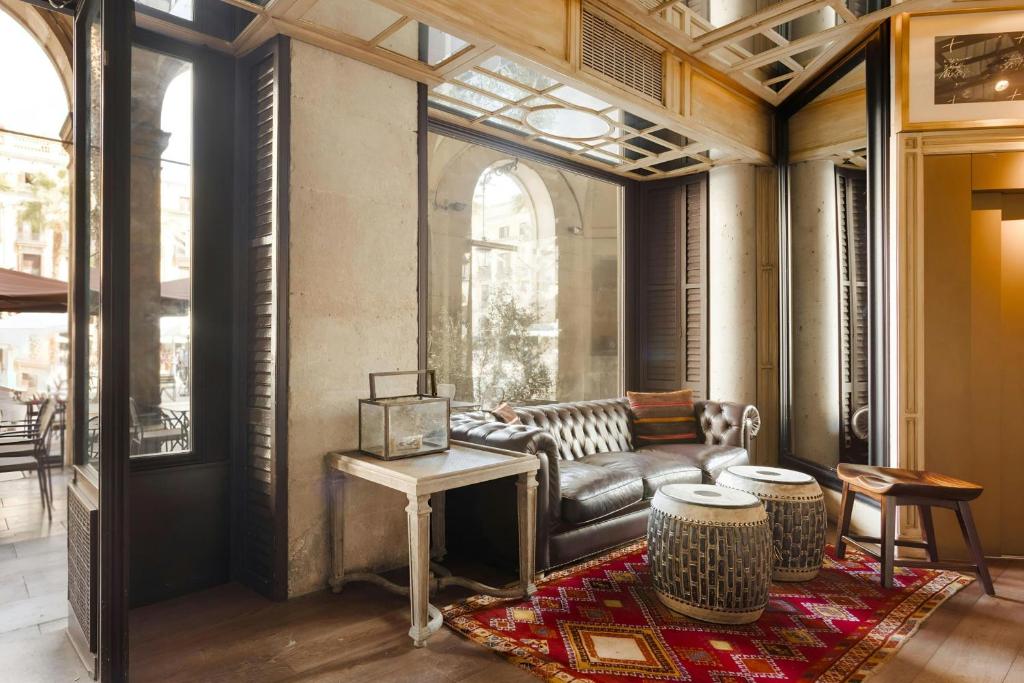 Lounge at Hotel DO: Plaça Reial with a leather Chesterfield sofa and tall windows looking onto the square