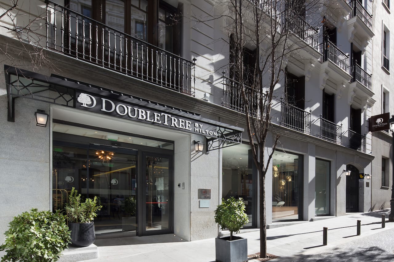The hotel's street-level entrance on a historic Madrid building, with iron balconies above and a DoubleTree by Hilton sign over the glass doors.