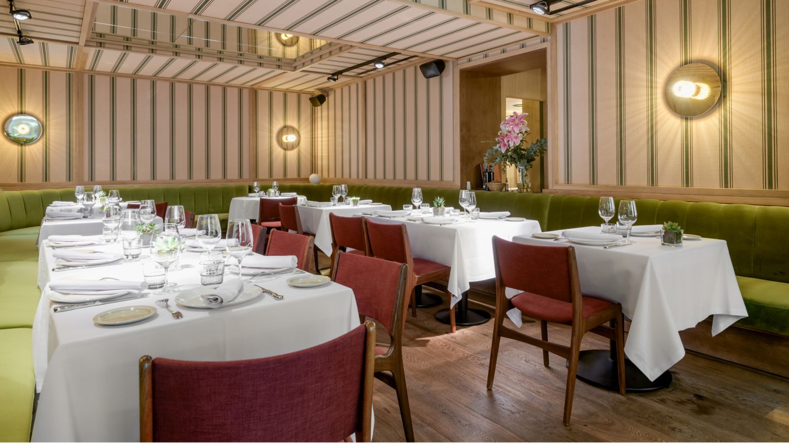 The restaurant: white-clothed tables with red chairs and a green velvet banquette running along striped fabric-panelled walls.