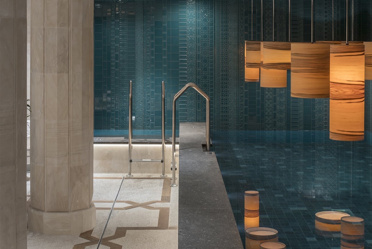 Indoor heated pool at El Llorenc's spa, with teal patterned tile walls and hanging wood lanterns