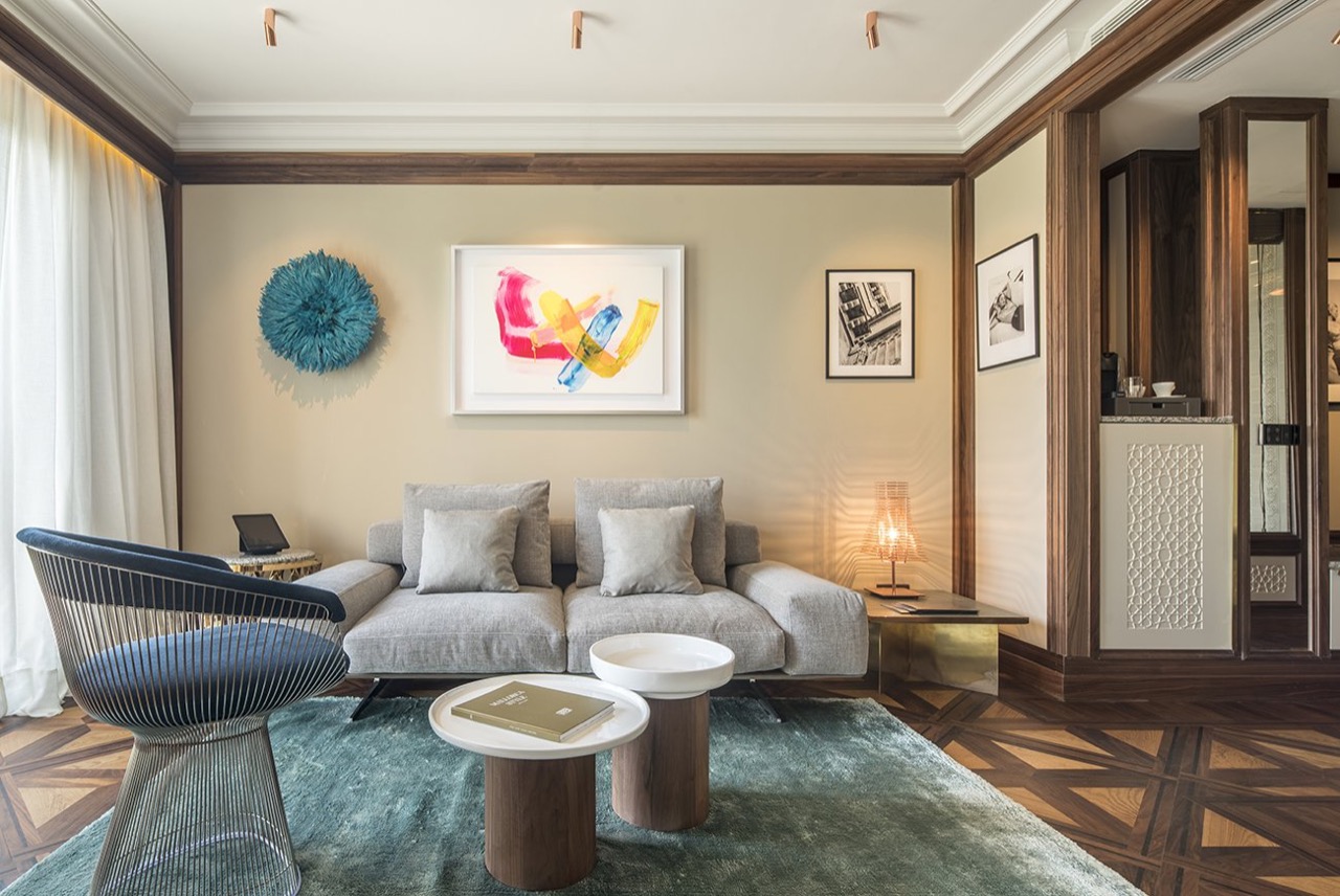 Suite living room at El Llorenc with a grey sofa, parquet flooring, and curated artwork on the walls