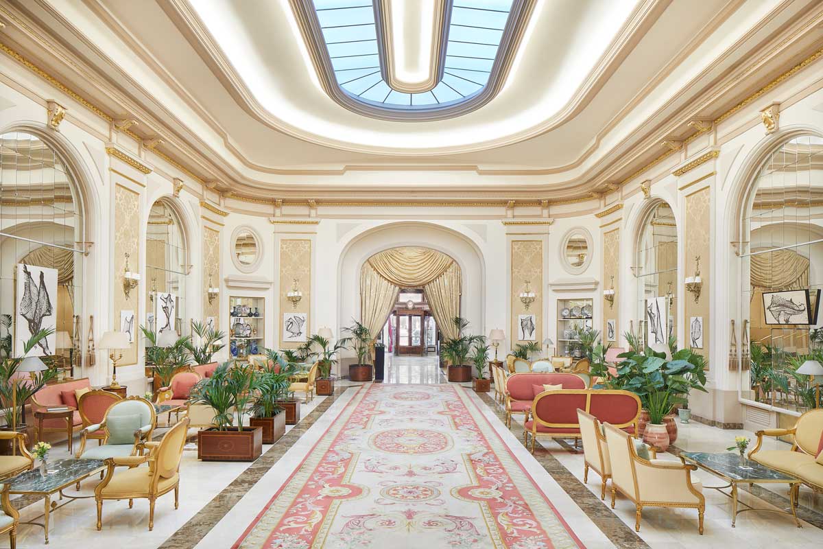The Grand Hall lobby with a skylight, a patterned rug and gilt-trimmed seating