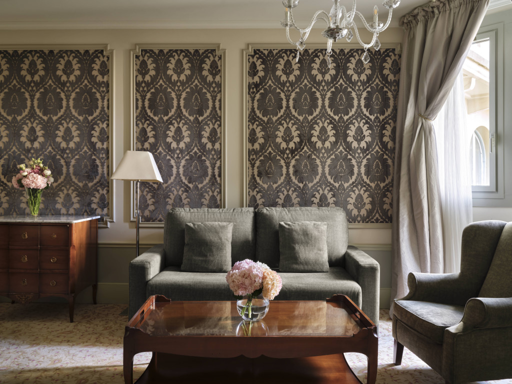 Superior Suite living room with a grey sofa, damask wall panels and a chandelier