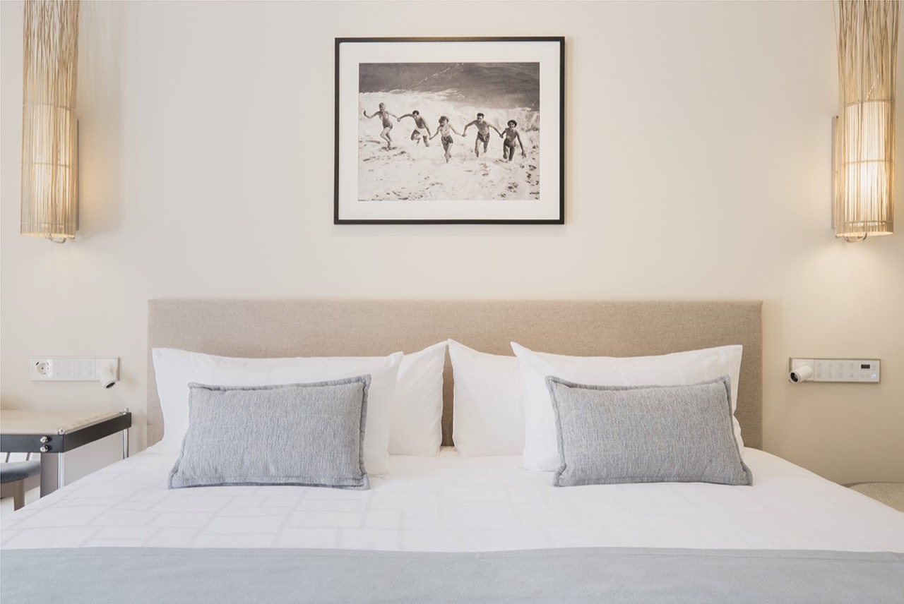 Bedroom with an upholstered headboard and framed beach photograph