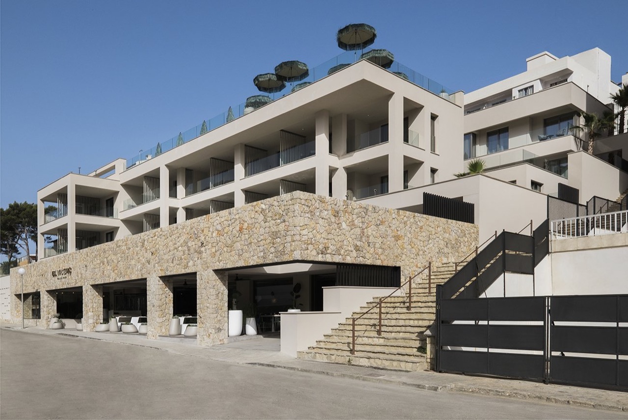Hotel facade with stone base, balconies and rooftop parasols