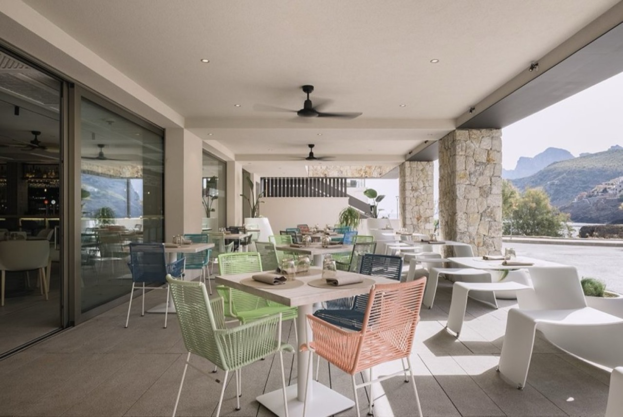 Restaurant terrace with colorful chairs overlooking the bay and cliffs