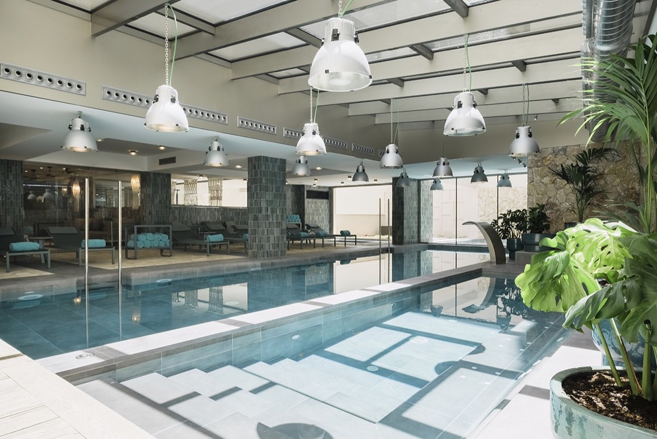 Indoor spa pool with loungers and stone wall detailing