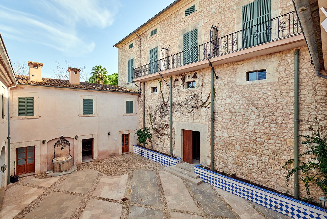 Stone courtyard with blue and white tiled edging between the old estate buildings