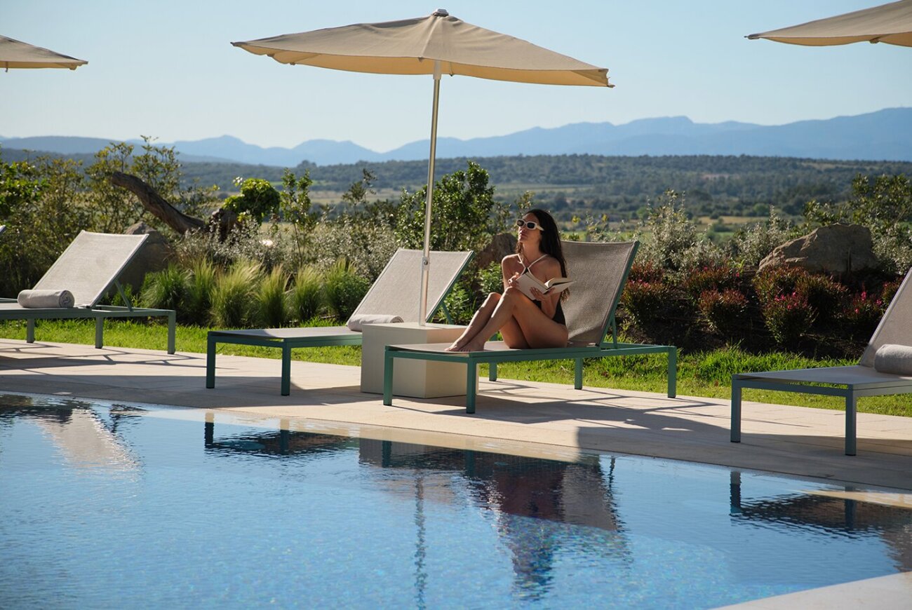Outdoor pool terrace with loungers, umbrellas and mountains in the distance