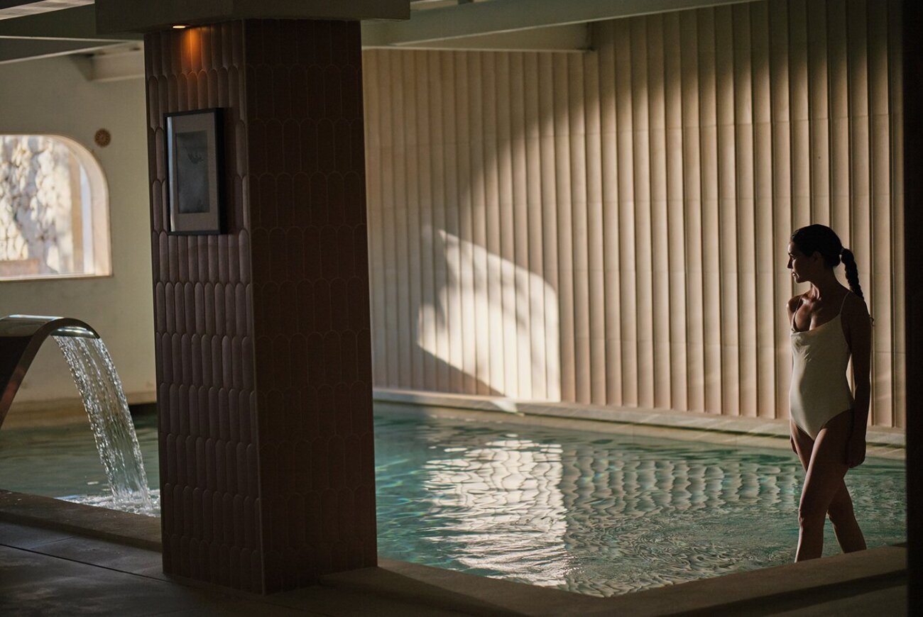 Indoor spa pool with a water feature and tiled walls