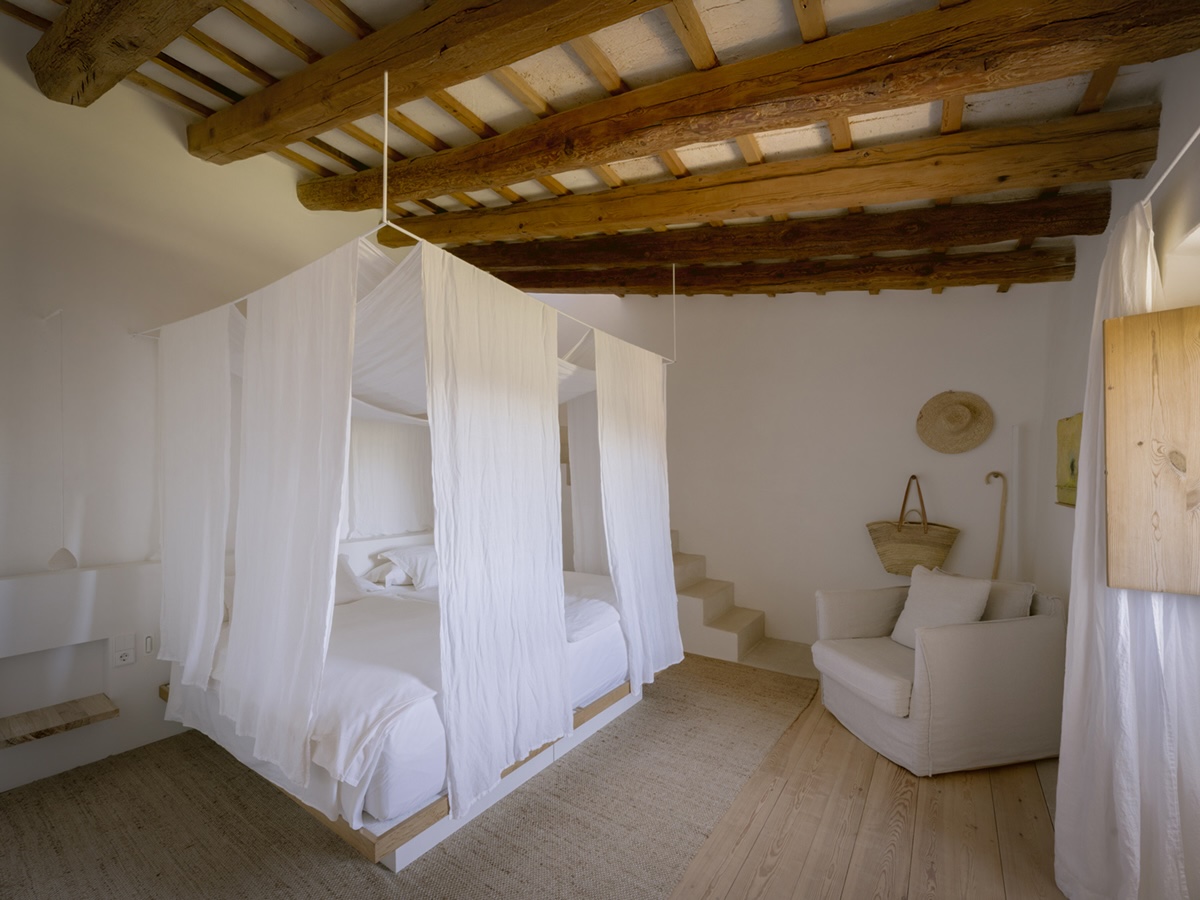 Bedroom with a white canopy bed under exposed wood beams