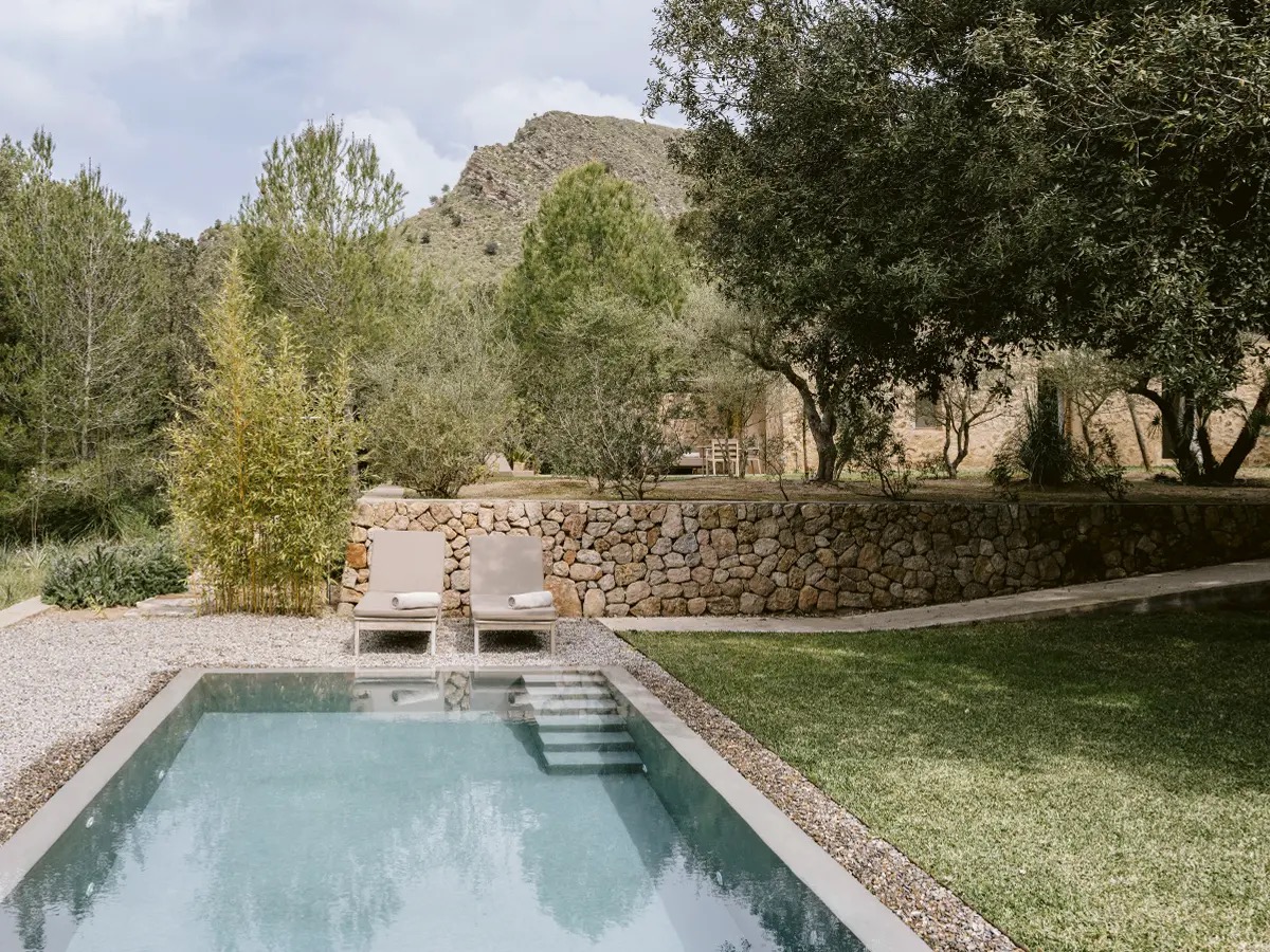 Private pool with loungers, a stone wall and hills behind