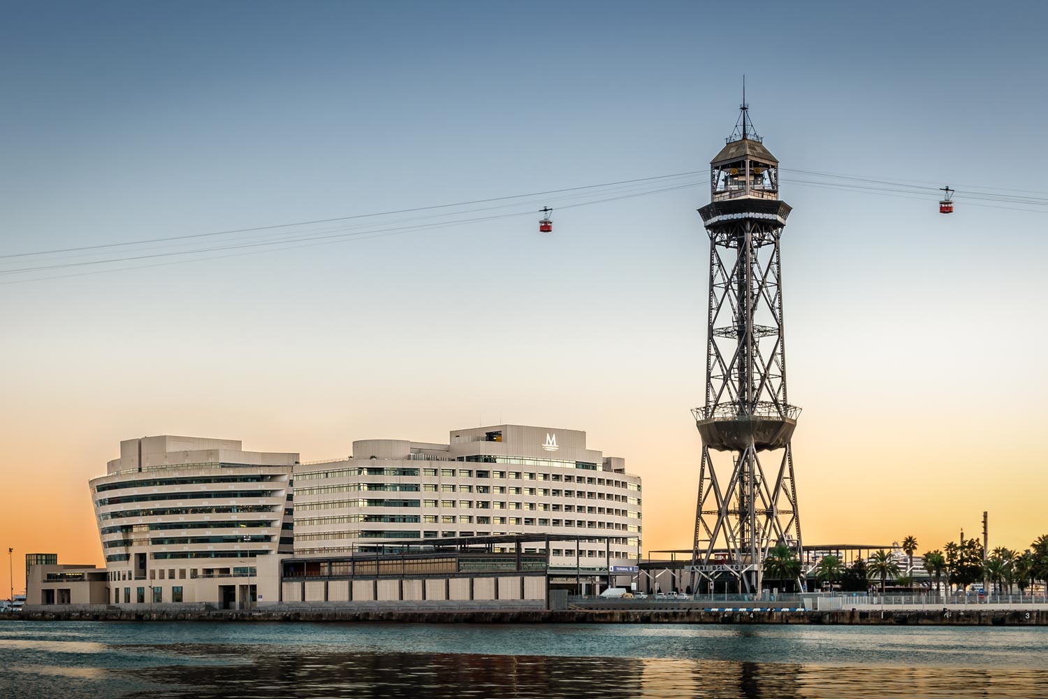 Eurostars Grand Marina exterior at dusk from the harbour with the cable-car tower
