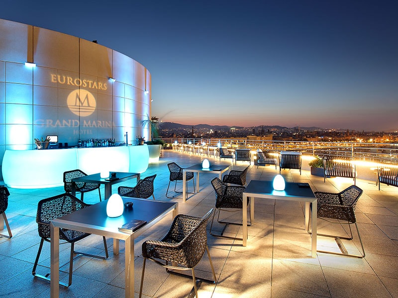 Rooftop bar terrace with illuminated hotel signage at dusk