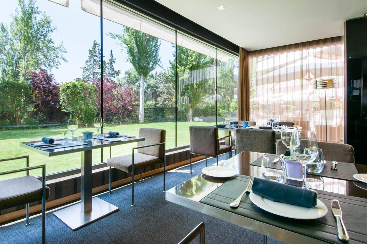 El Ventanal restaurant's dining room, set tables against a full-height glass wall looking onto the hotel's lawn and garden.