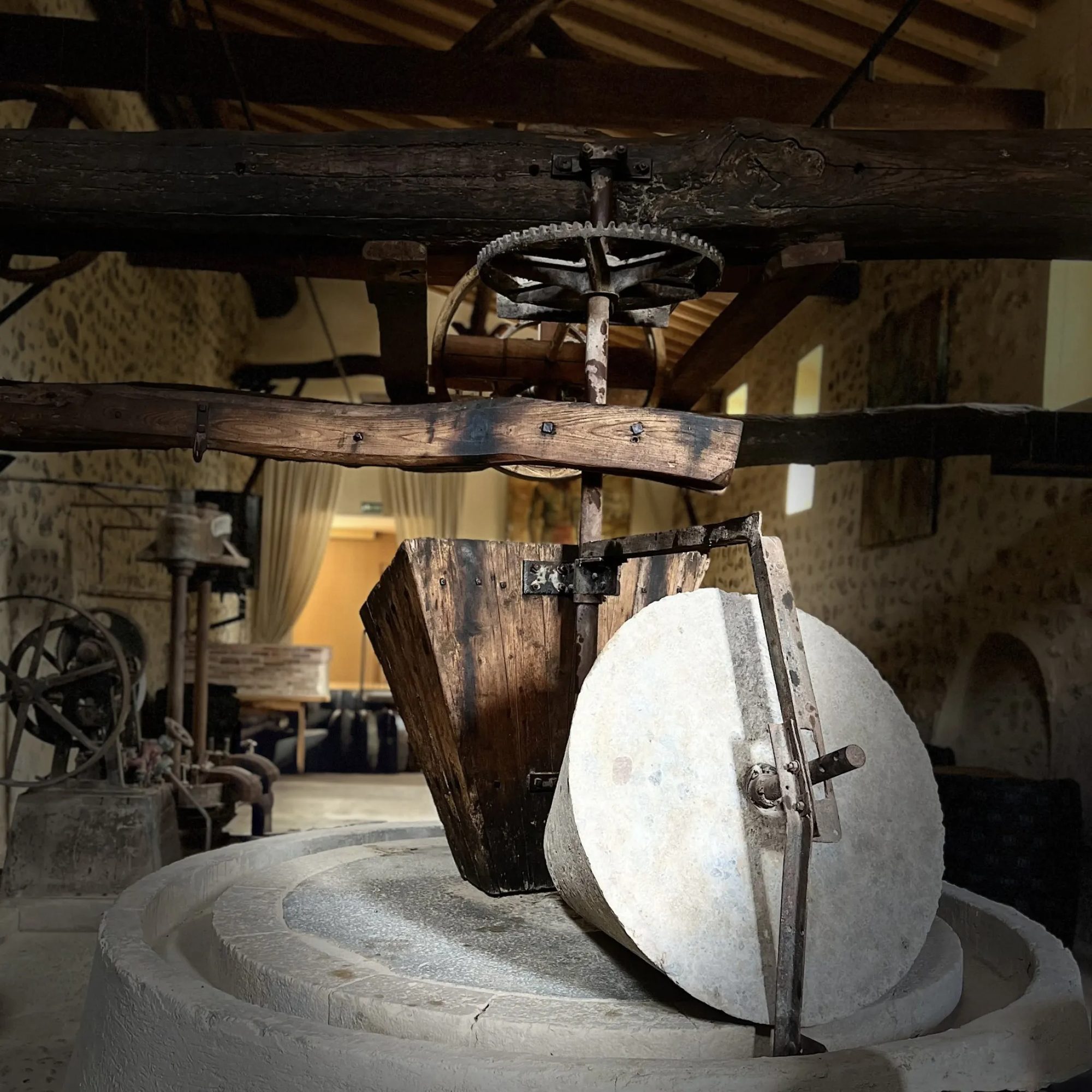Preserved stone olive press (tafona) on display inside Finca Banyols' restaurant, with its wood beam and pulley mechanism intact