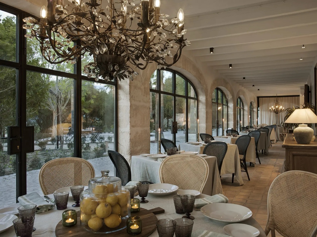 Jacaranda Restaurant's arched dining room at Finca Serena, set with tables under a chandelier