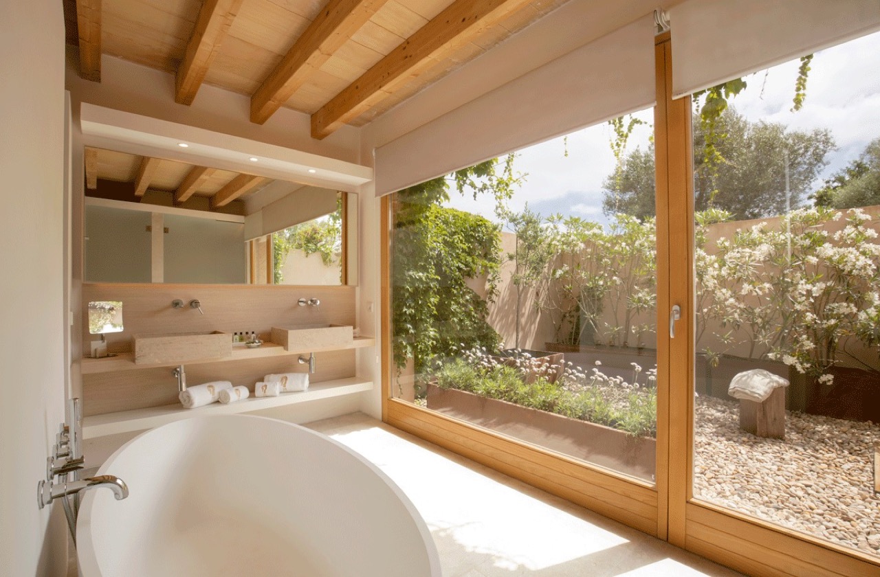 Room bathroom at Fontsanta Hotel with a freestanding tub facing a private garden through floor to ceiling glass