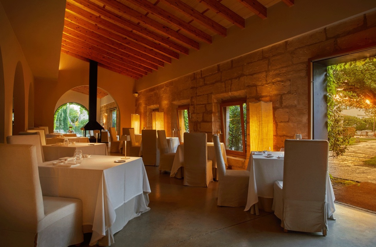 Restaurant dining room at Fontsanta Hotel with exposed stone walls and a wood beam ceiling