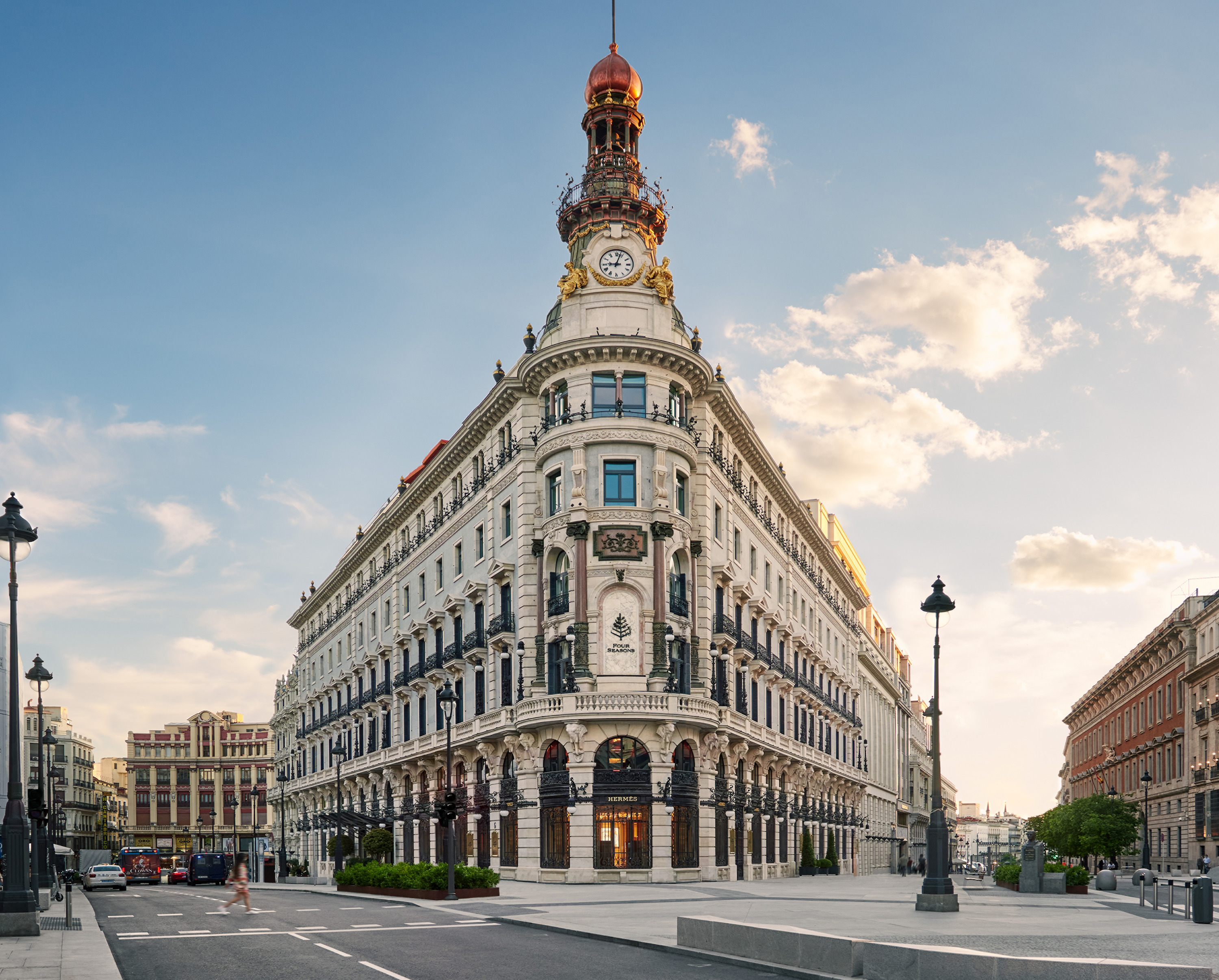 Corner facade of the ornate stone building with a domed clock tower and Four Seasons signage set into a marble niche above street level.