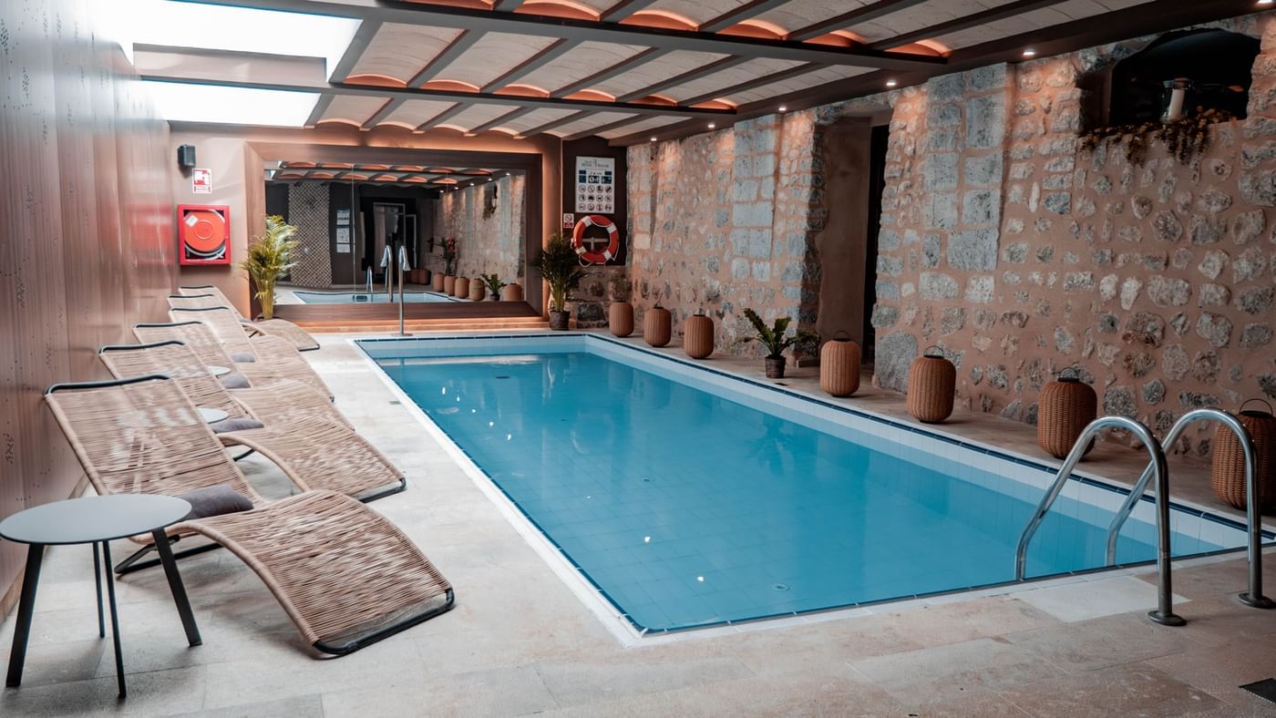 Indoor spa pool inside a stone vaulted room with loungers