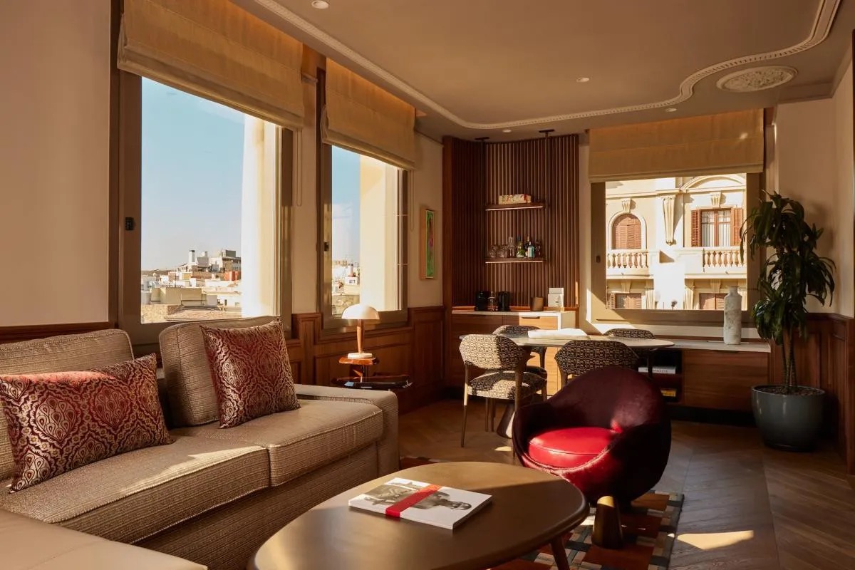Grand Suite living area with a sofa, city-view windows and a terracotta armchair
