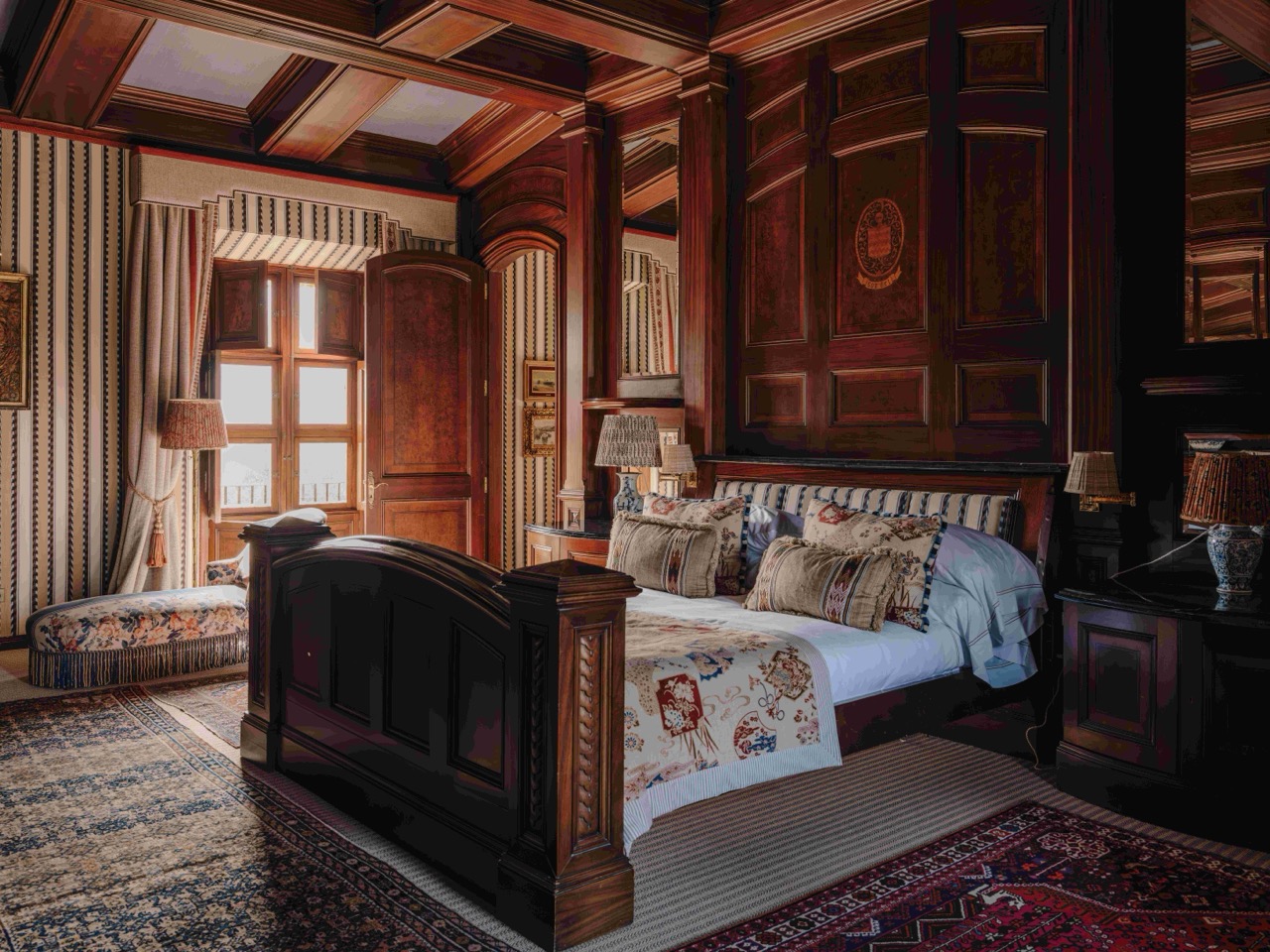 Grand suite bedroom with dark wood paneling and a carved four poster bed