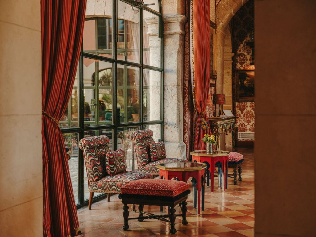 Lounge with patterned armchairs and striped curtains behind arched stone columns
