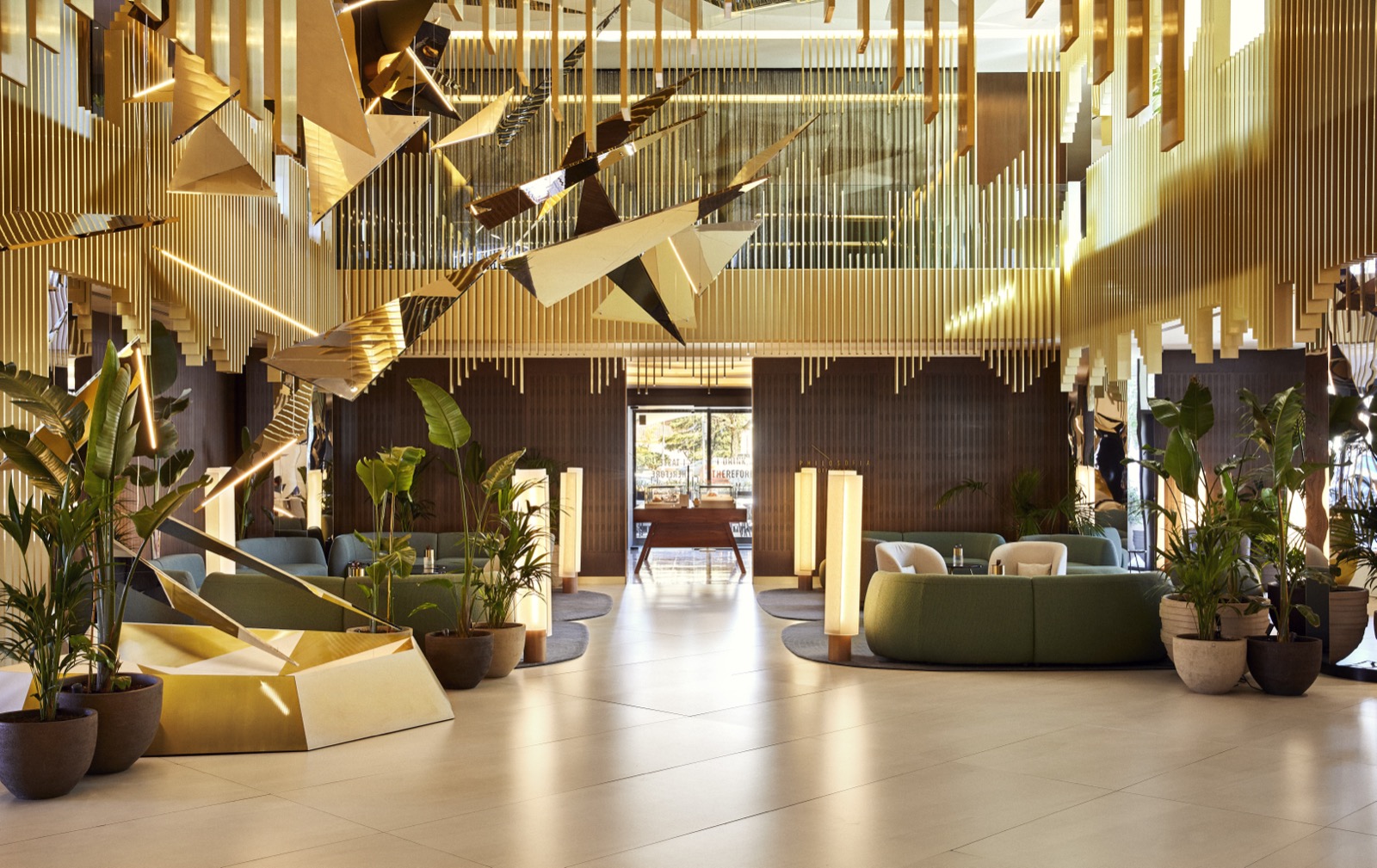 Lobby with a brass origami-bird sculpture and green lounge seating