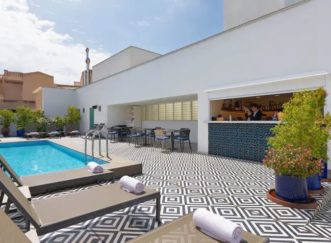 TopOn rooftop terrace at H10 Metropolitan with a small plunge pool, sun loungers, and graphic black-and-white tile flooring