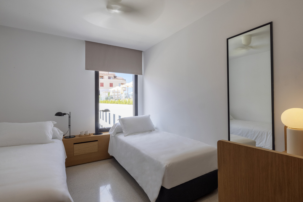 Bright twin room at HM Palma Blanc with two single beds, a full-length mirror and a window looking onto the street.