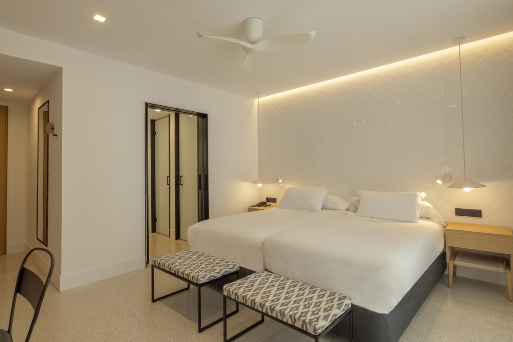 Twin room at HM Palma Blanc in the evening, with two beds pushed together, upholstered benches and terrazzo flooring.