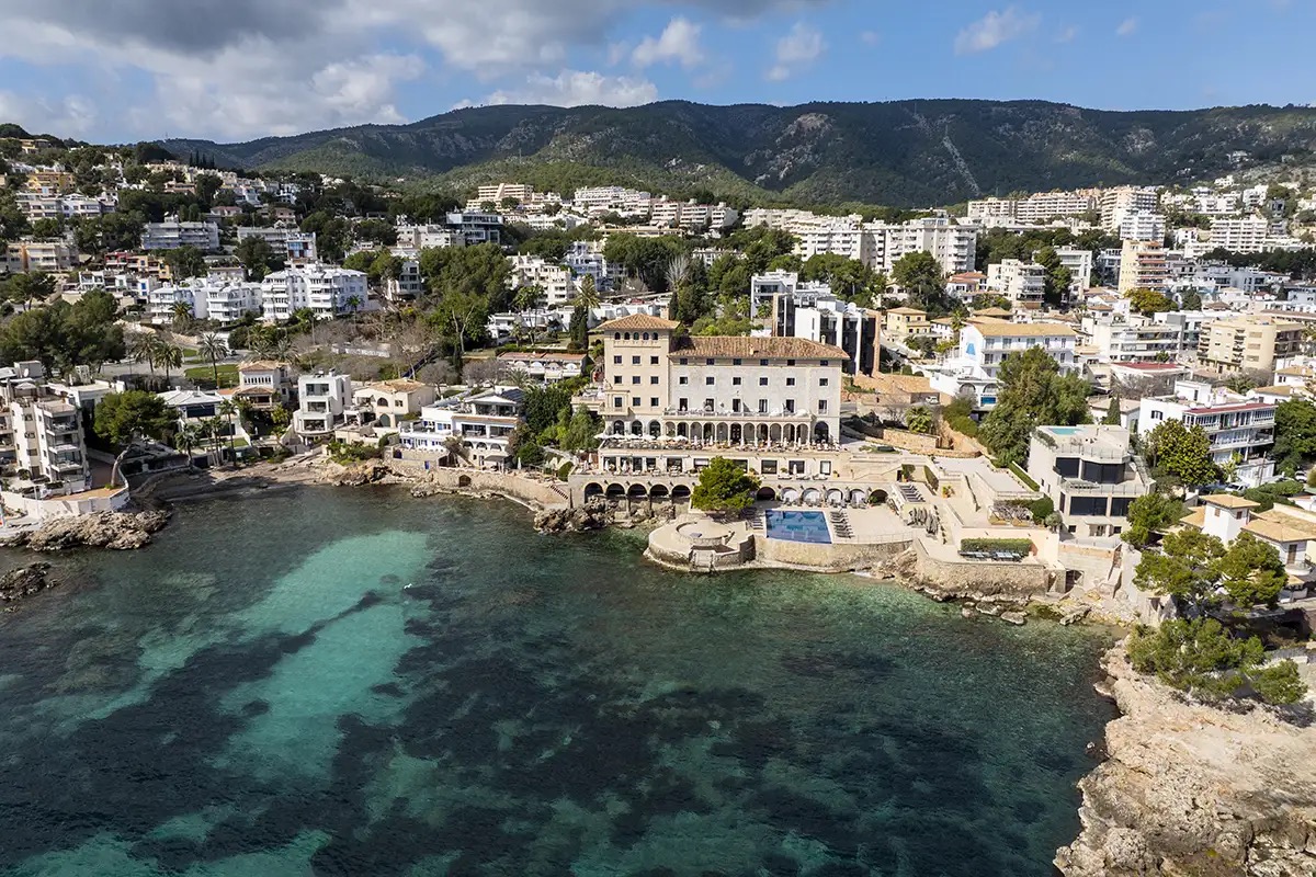 Aerial view of the hotel building on a rocky cove with pool terrace
