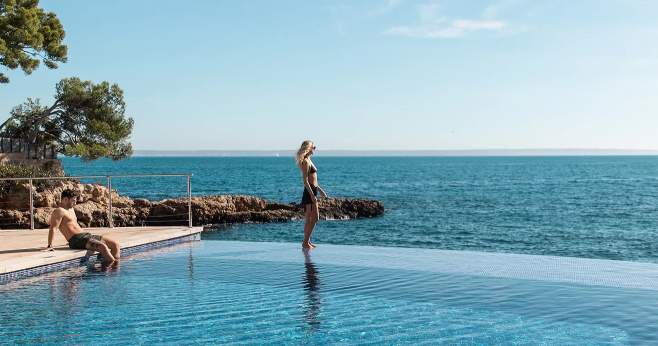 Infinity pool merging into the sea with guests at the edge