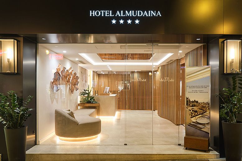 Illuminated glass entrance with the Hotel Almudaina sign and four-star marking above the doors