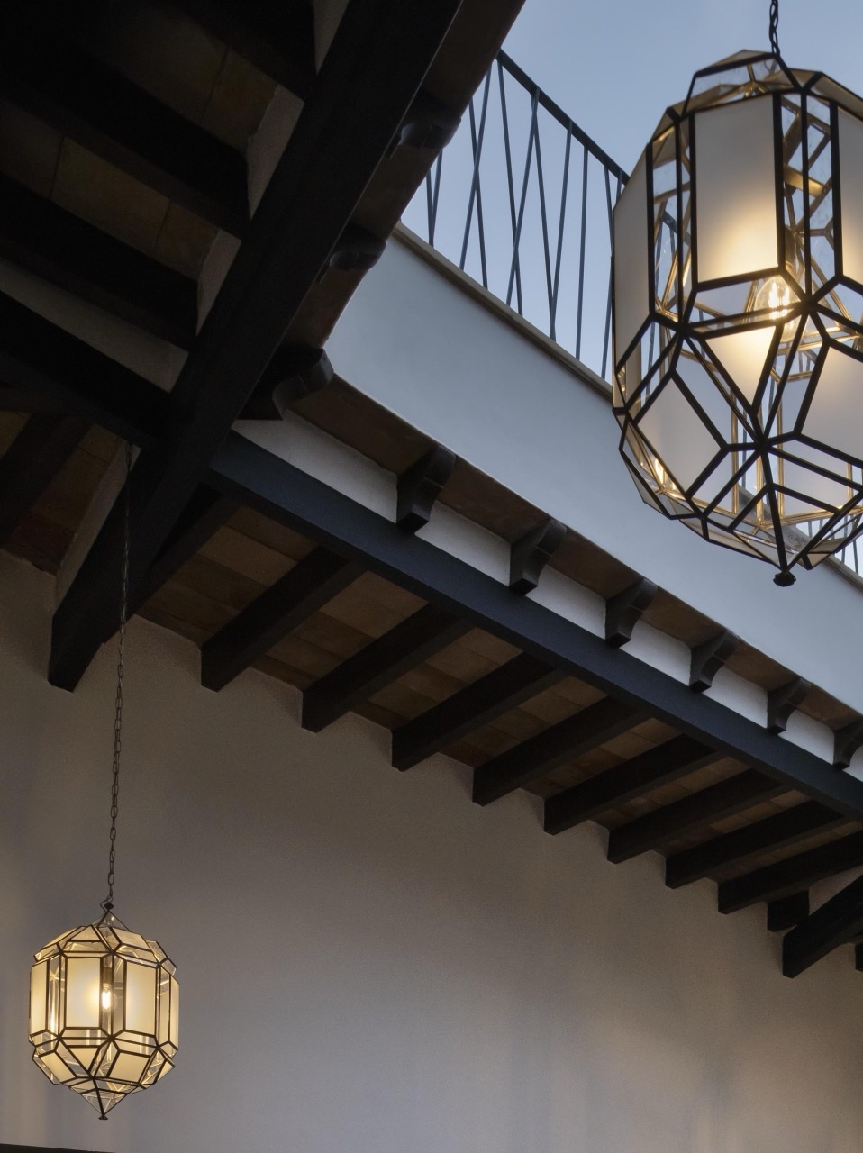 Wooden beamed ceiling and staircase with hanging lantern lights inside the historic house