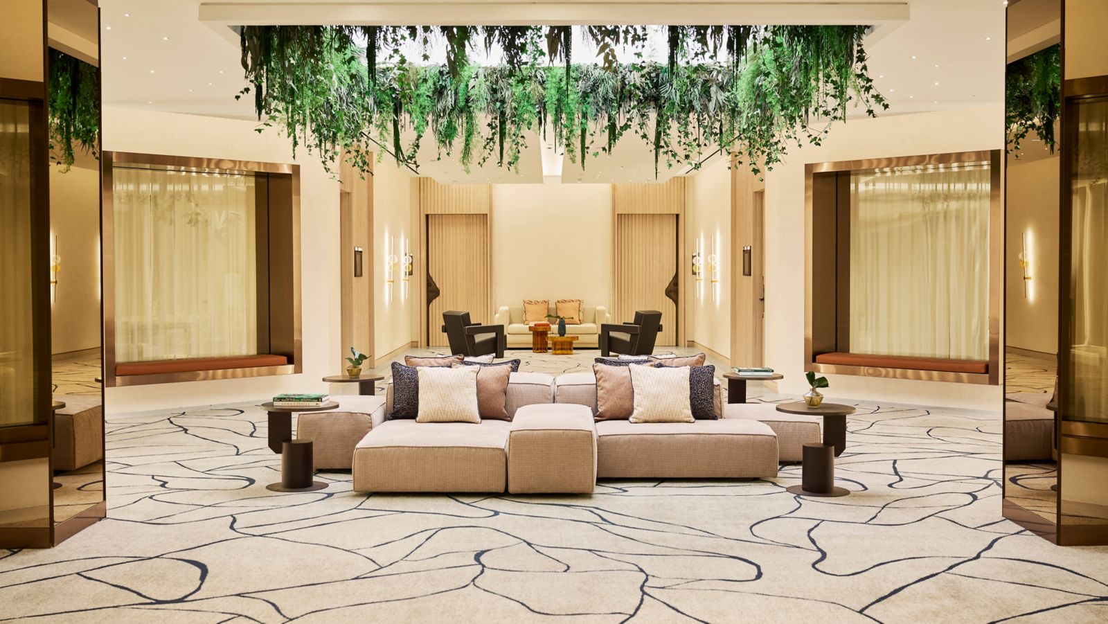 Lobby lounge with a hanging greenery installation and neutral-toned seating
