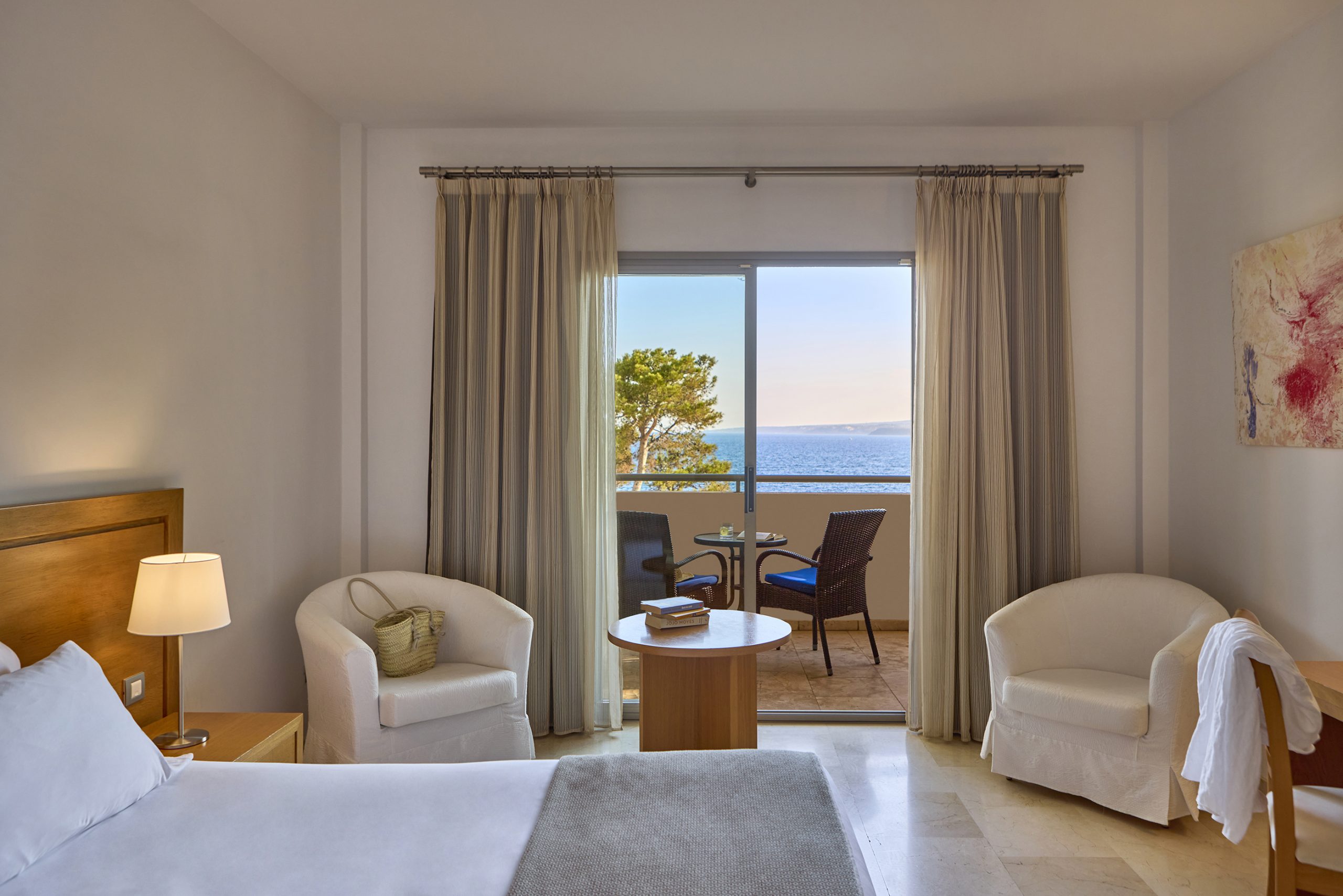 Sea-view double room with a private balcony, wicker chairs and a table looking out over the water