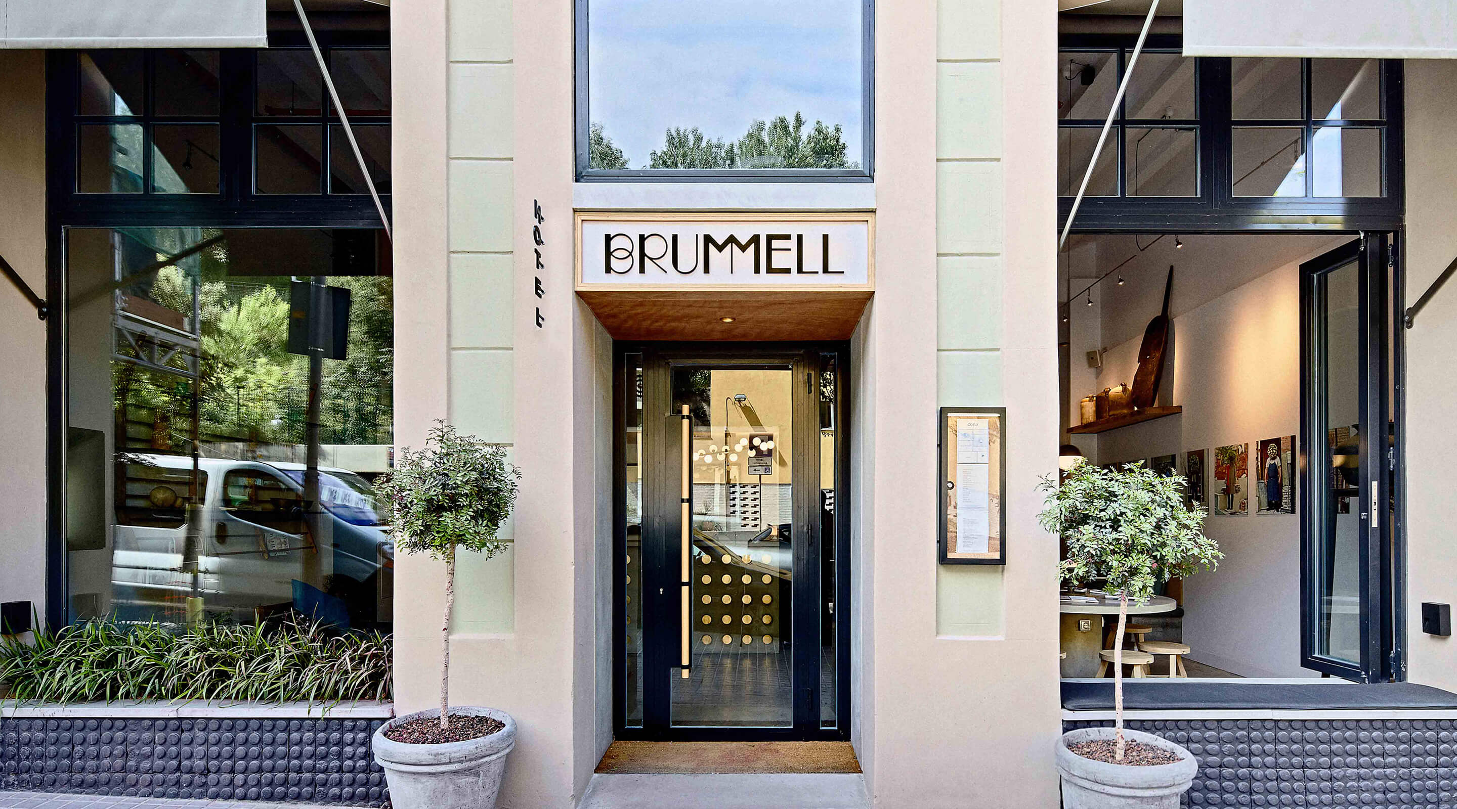 Hotel Brummell's entrance on Carrer Nou de la Rambla, with the BRUMMELL sign above a glass door and clipped trees in pots either side