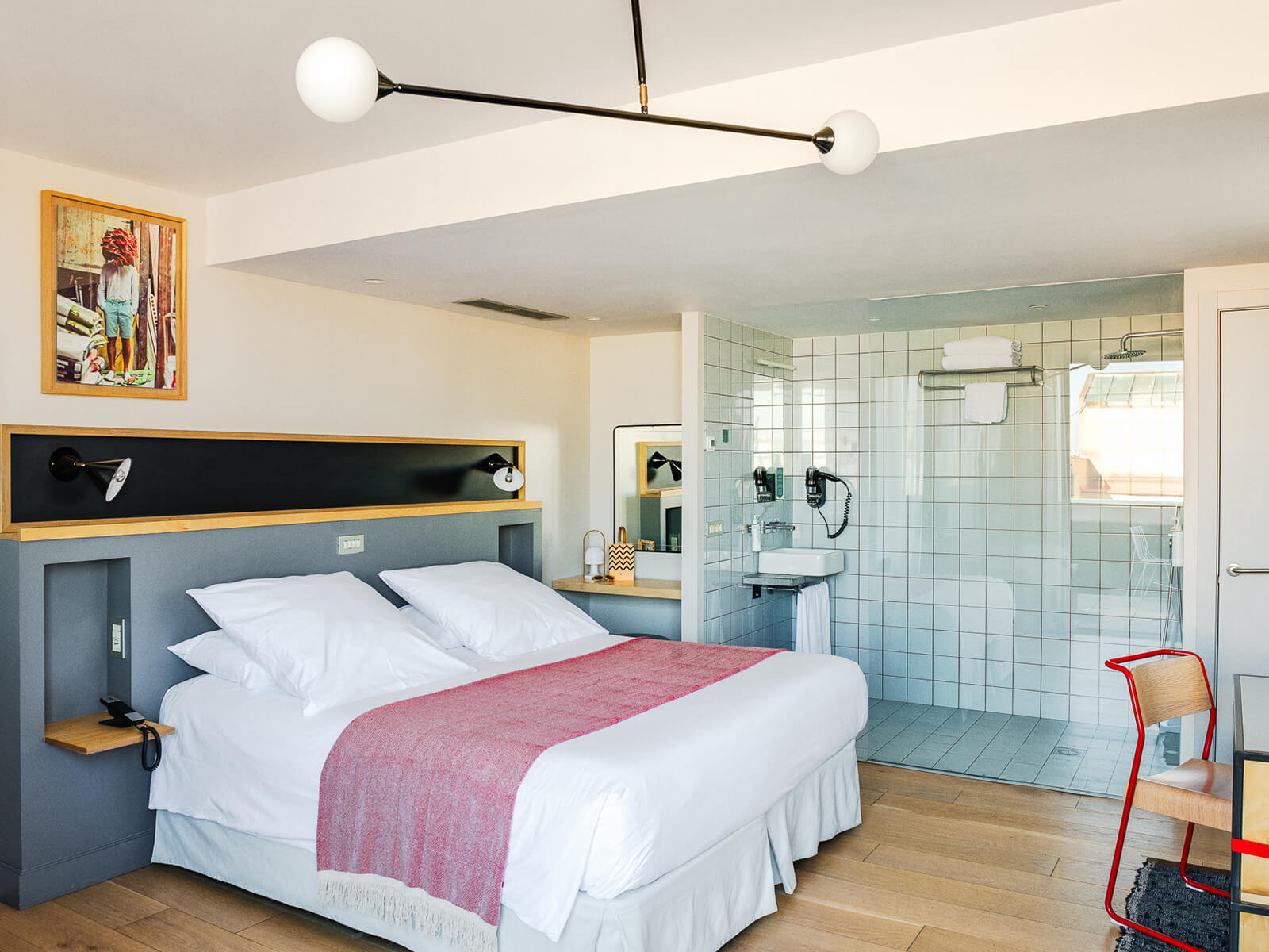 Penthouse room with a double bed, a grey headboard with wall-mounted reading lamps, and an open green-tiled shower alongside