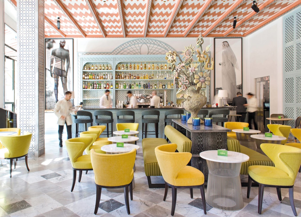 Hotel bar and lounge with yellow armchairs and a stocked back bar