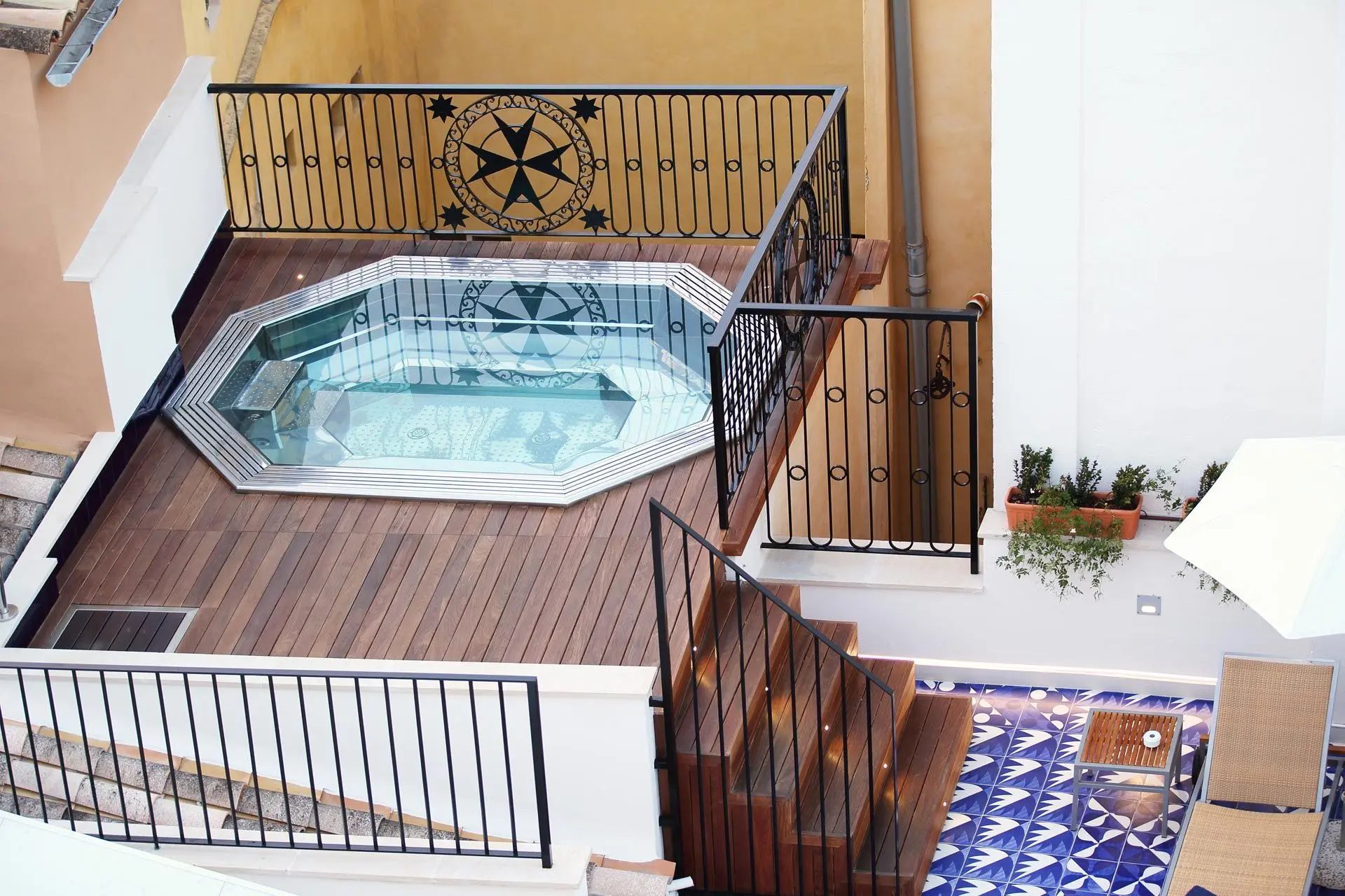 Octagonal rooftop plunge pool at Hotel Cort with a tiled Mallorcan cross motif on the pool floor and wrought-iron balustrades around a wood deck
